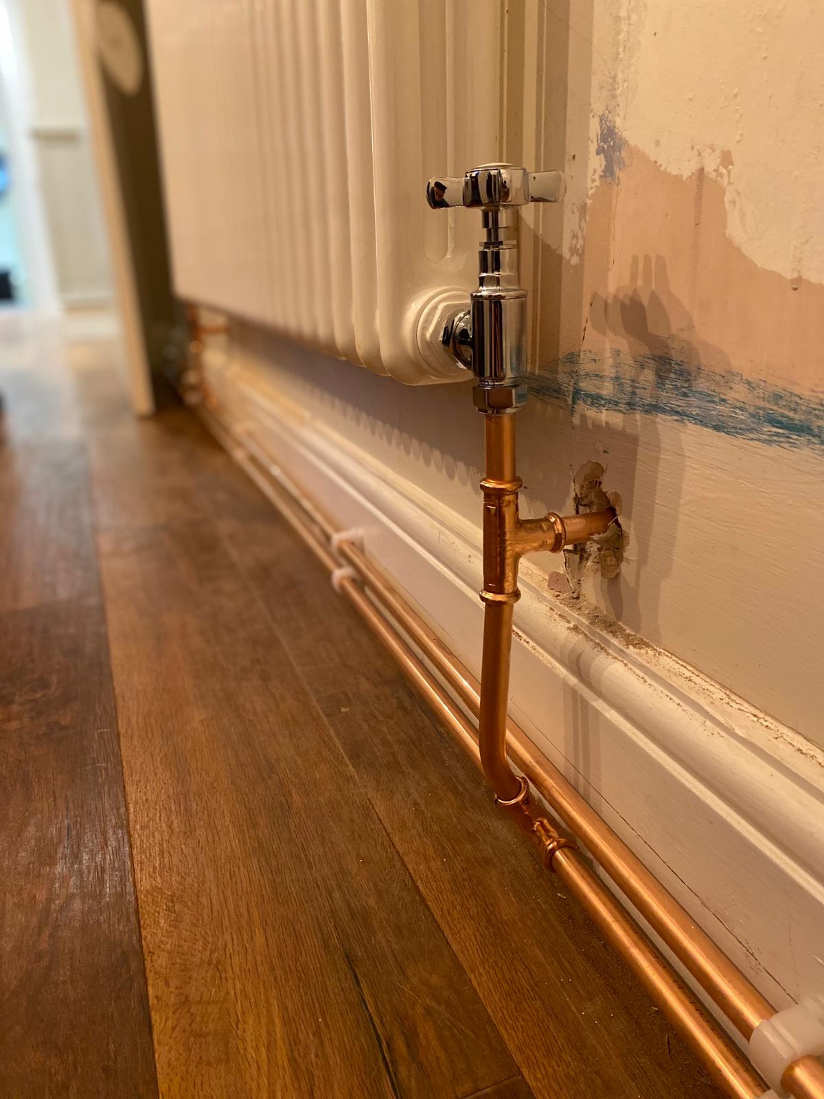 Radiator valve and copper pipework connection detail close-up