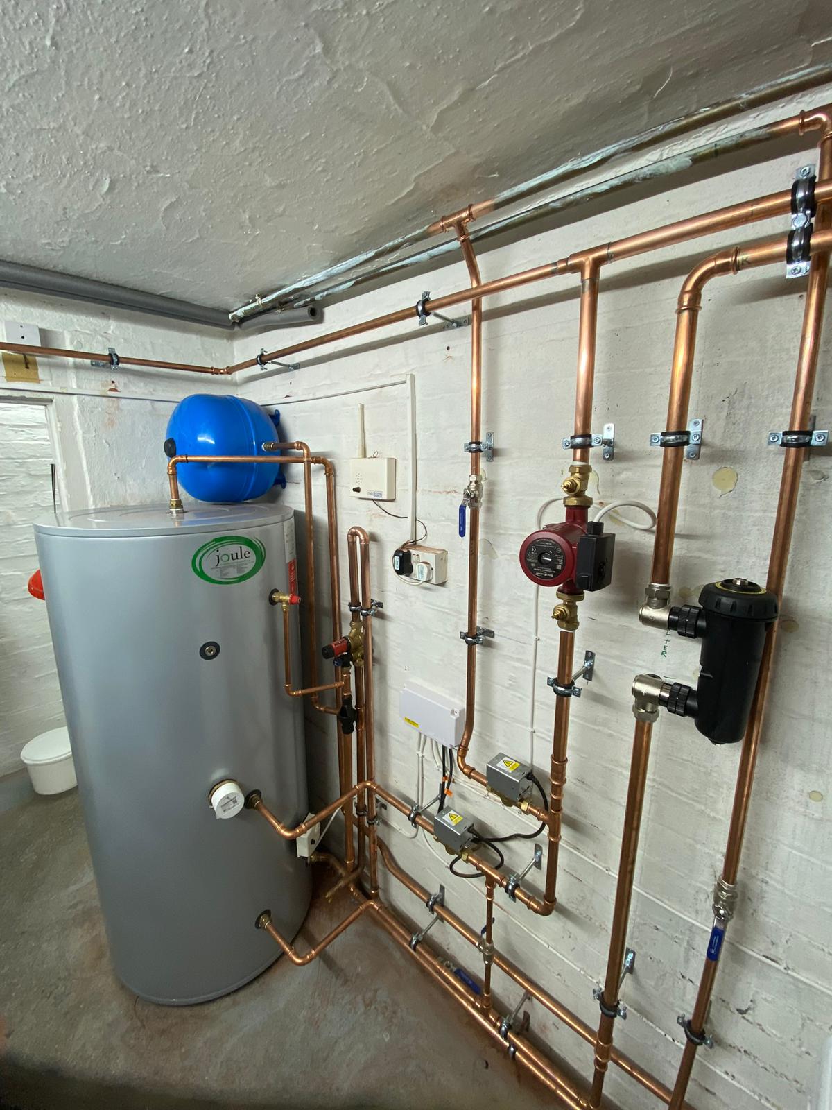 Complete plant room installation with cylinder, pump, and copper pipework