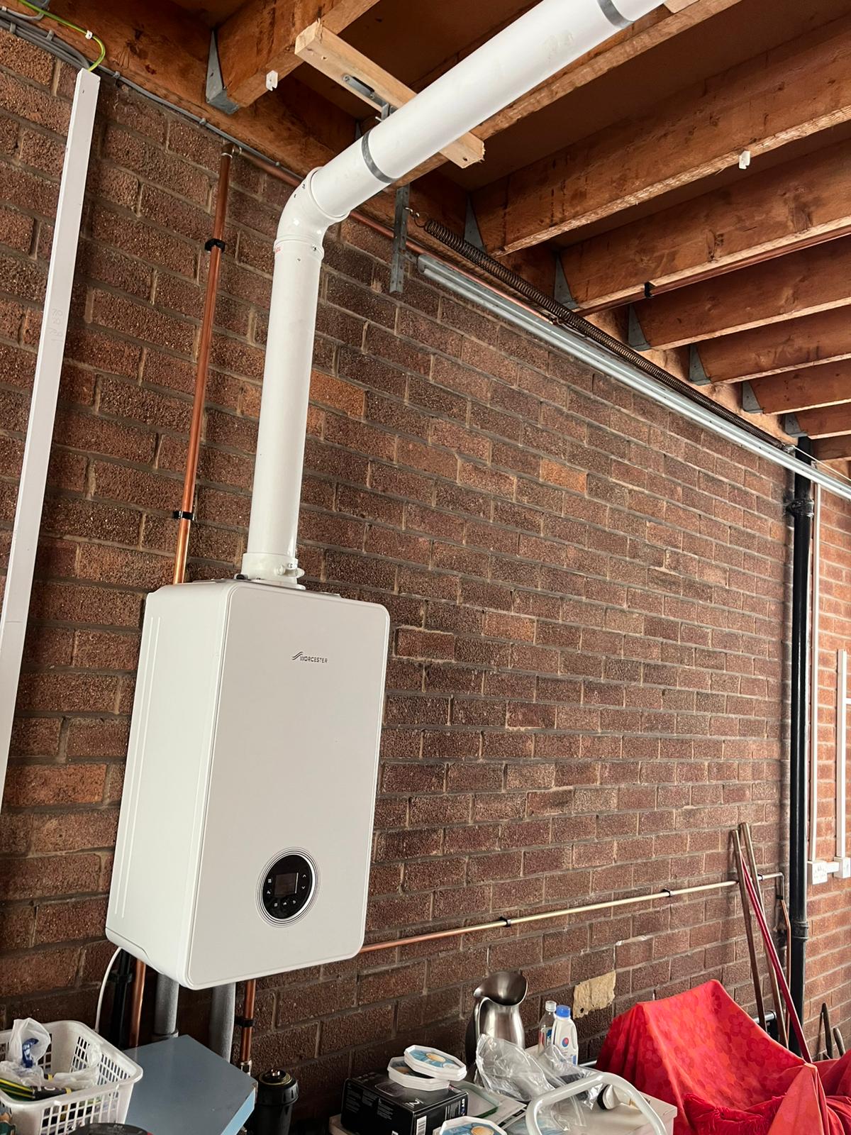 Worcester Bosch boiler mounted on brick garage wall with flue
